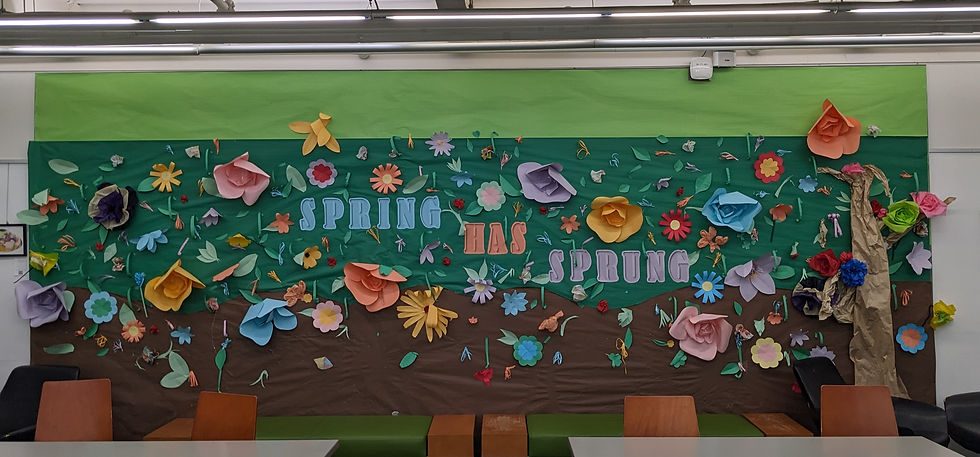 green wall with the words spring has sprung and paper flowers