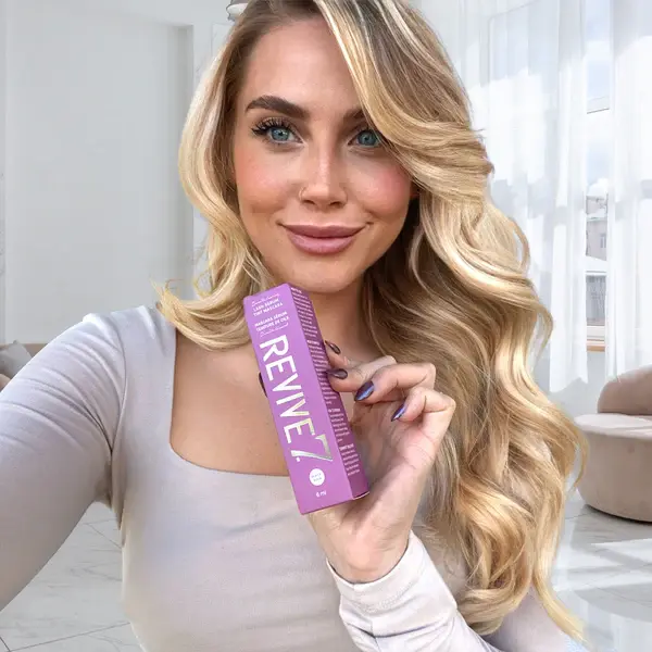 Beautiful blond girl holding Revive7 Revitalizing Lash Serum Volume Mascara