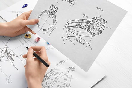 Jeweler with sketches of elegant jewelry at white wooden table, closeup.jpg