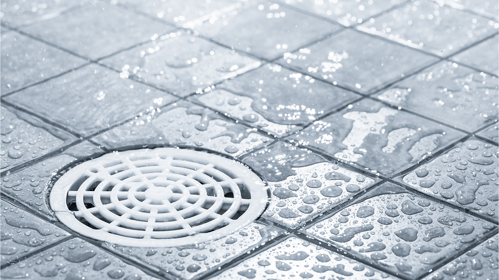 A floor drain surrounded by wet tiles and soap suds scattered around.