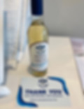 Bottle of Pinot Grigio white wine with a "Thank You" note card on a white table.