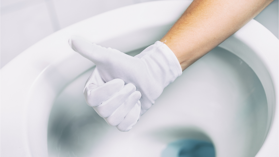 A person working on a toilet bowl filled with water.