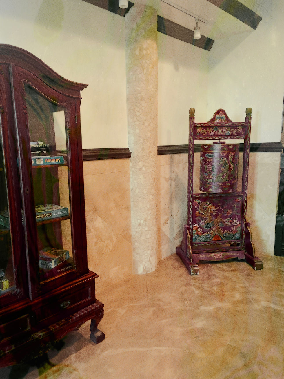 Ornate wooden furniture in a beige room with art deco details. A glass cabinet with books is on the left; a dragon-themed chair on the right.