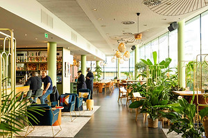 Bright hotel restaurant interior with plants and large windows, photographed in Paris