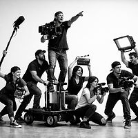 צוות הפקת וידאו וקולנוע מקצועי בפעולה, מצויד במצלמות, מיקרופון בום ותאורת סטודיו על רקע לבן נקי