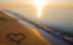 sand heart next to sunset
