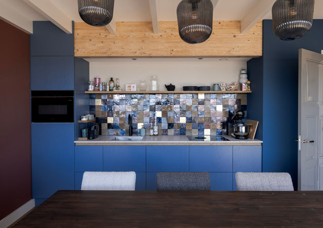 Blauwe maatwerk keuken met eiken details en kleurrijke tegelachterwand