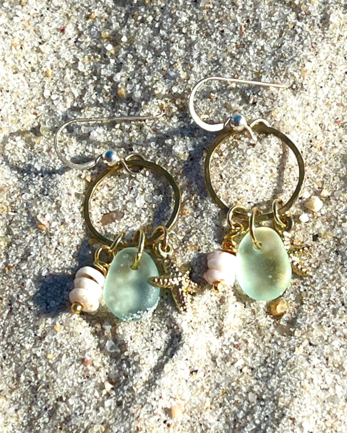 Thumbnail: gold sea glass charm earrings on sand