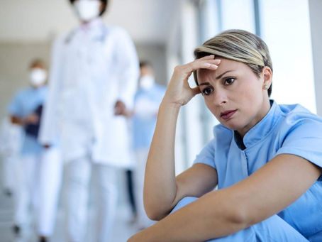 A stressed healthcare worker suffering the effects of poor cleaning and disinfection on medical equipment during medical procedures. Learn how to reduce sick days in Miami hospitals.