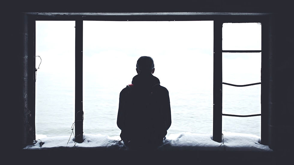 Silhouette of a person sitting by a large window, overlooking a bright, snowy seascape. Snow on the windowsill, creating a calm mood.