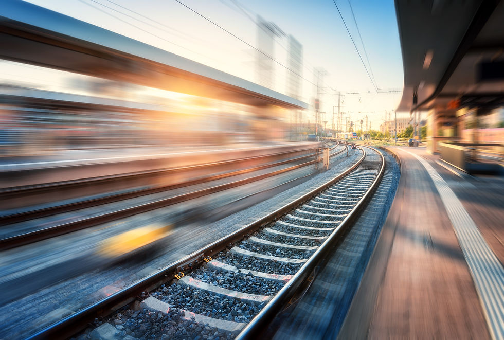 A train driving by with motion blur. A train track and a station. 