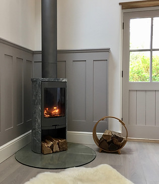 A hygge corner is created by a modern curvy soapstone logburner stove and large cosy sheepskin rug by Cid Carr Interior Design #hygge #cosy #interiors #modern #contemporary #interiordesign #professional #Contura #stove #sexy #stone #warm #panelling #timber #floor #floors #flooring #natural #texture #materials