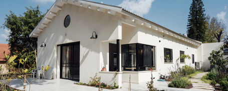 גג רעפים דו-שיפועי עם קונסטרוקציית עץ גושני גלויה, מבט חיצוני בזווית מצד ימין על בית פרטי בסגנון כפרי