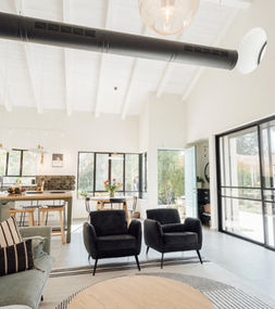 גג רעפים דו-שיפועי עם קונסטרוקציית עץ גושני גלויה בסגנון כפרי, מבט פנימי לחלל פתוח