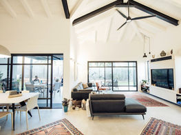 גג רעפים גושני גלוי, קונסטרוקצייית התקרה בנויה מגלרייה וקורות גושני בגוון לבן בשילוב קונסטרוקציית מתכת בגוון שחור, מבט מהסלון אל החוץ, בית פרטי בקווים נקיים