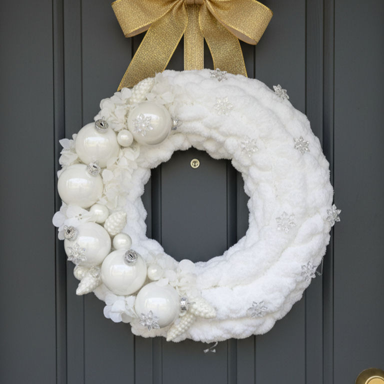 Couronne de Noël blanche cocooning avec boules nacrées et flocons scintillants.