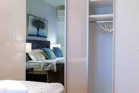 The reflection of the double bed in the wardrobe mirror