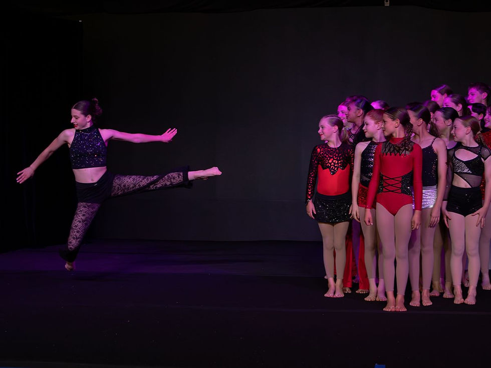 One performer leaping away from a group of performers in red, black and silver costumes