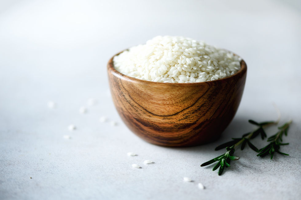 Riz jasmin cru dans un bol en bois sur fond clair, prêt à être cuisiné pour des recettes thaïlandaises authentiques.