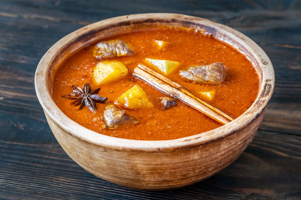 Un bol en bois contenant un curry Massaman thaïlandais avec des morceaux de bœuf tendres, des pommes de terre dorées, des bâtons de cannelle et de l’anis étoilé, le tout dans une sauce riche et épicée.