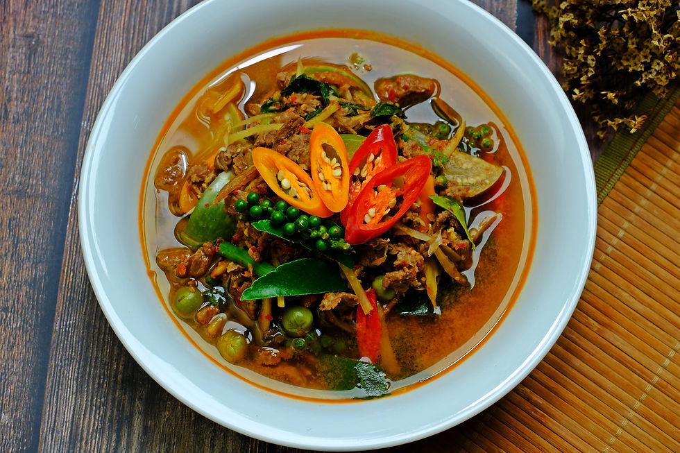 Un bol de Kaeng Pa (Curry Thai Jungle) garni de piments rouges frais, de poivre vert et de feuilles de combava. Ce curry sans lait de coco est intensément parfumé et épicé.