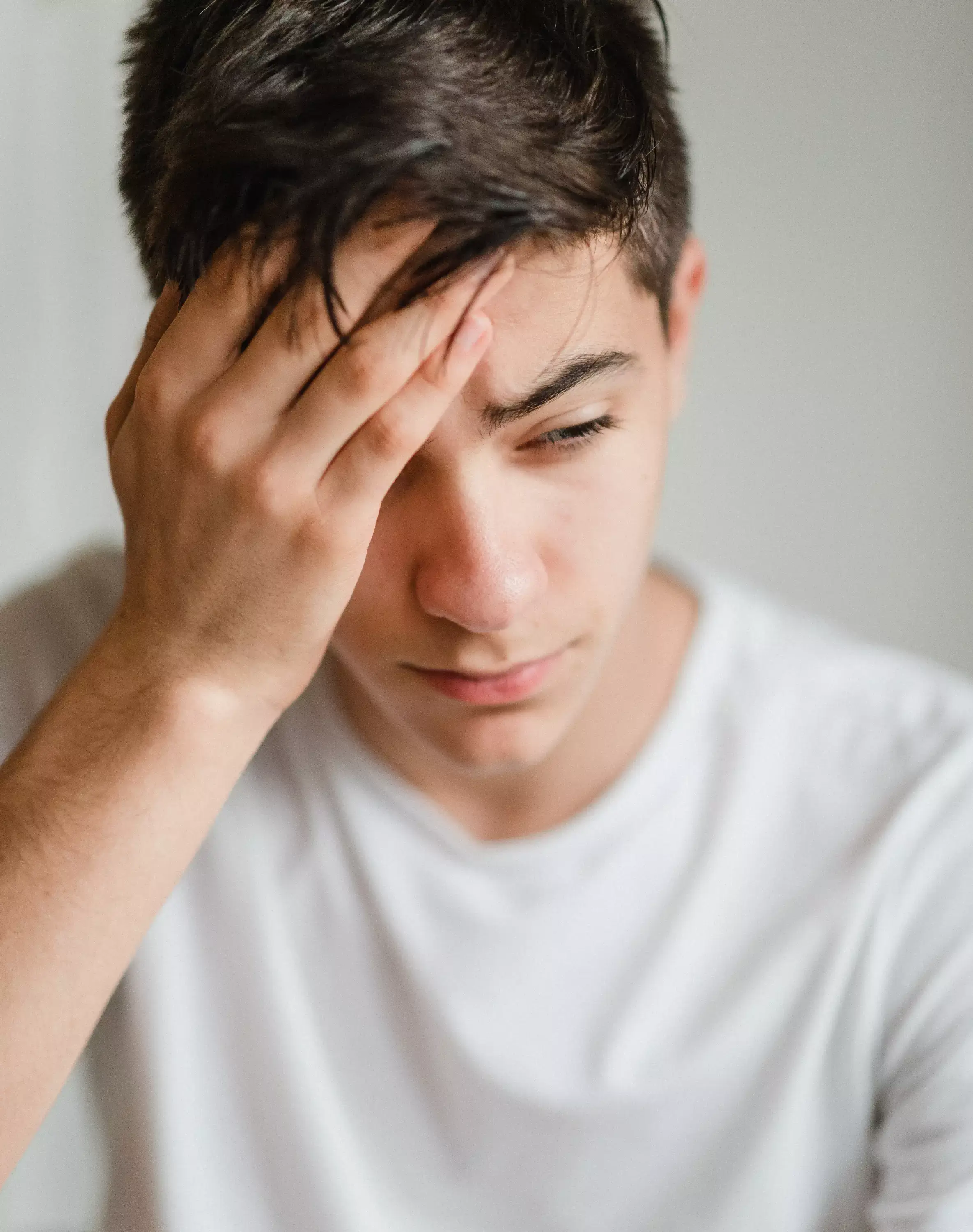 Man covering his face with his hand, hoping for pain management.webp