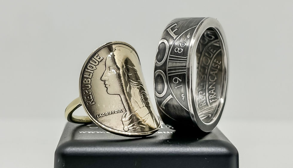 Bague en pièce de monnaie, gravée "République Française" et dates. Pose sur boîte noire, fond blanc, tons argentés et dorés.