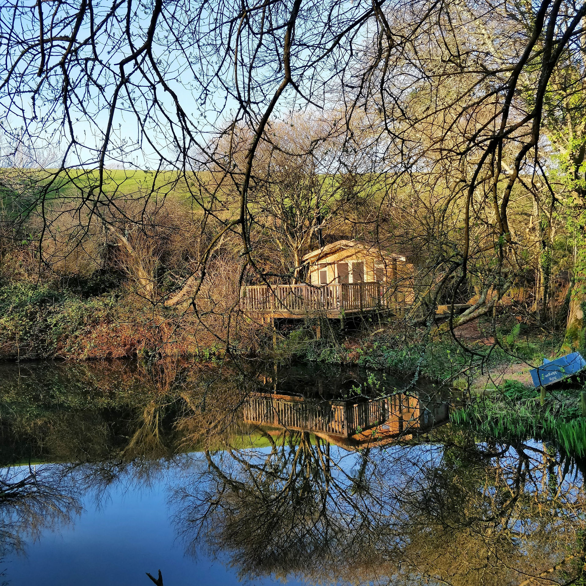 Wooden cabin seen across the pond through the woods