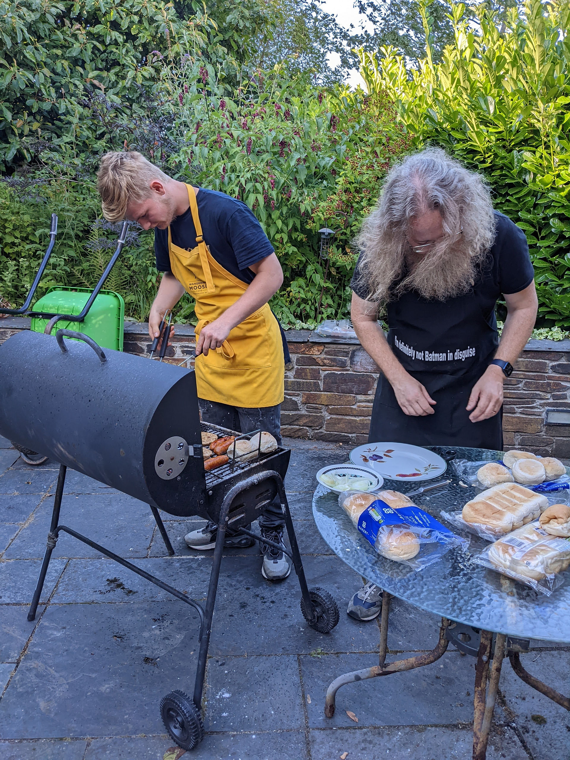 Two men, cooking on a bbq.