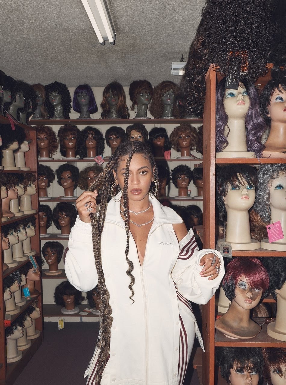 beyonce inside of a wig room at a beauty supply store wearing Ivy Park and blonde jumbo braids.
