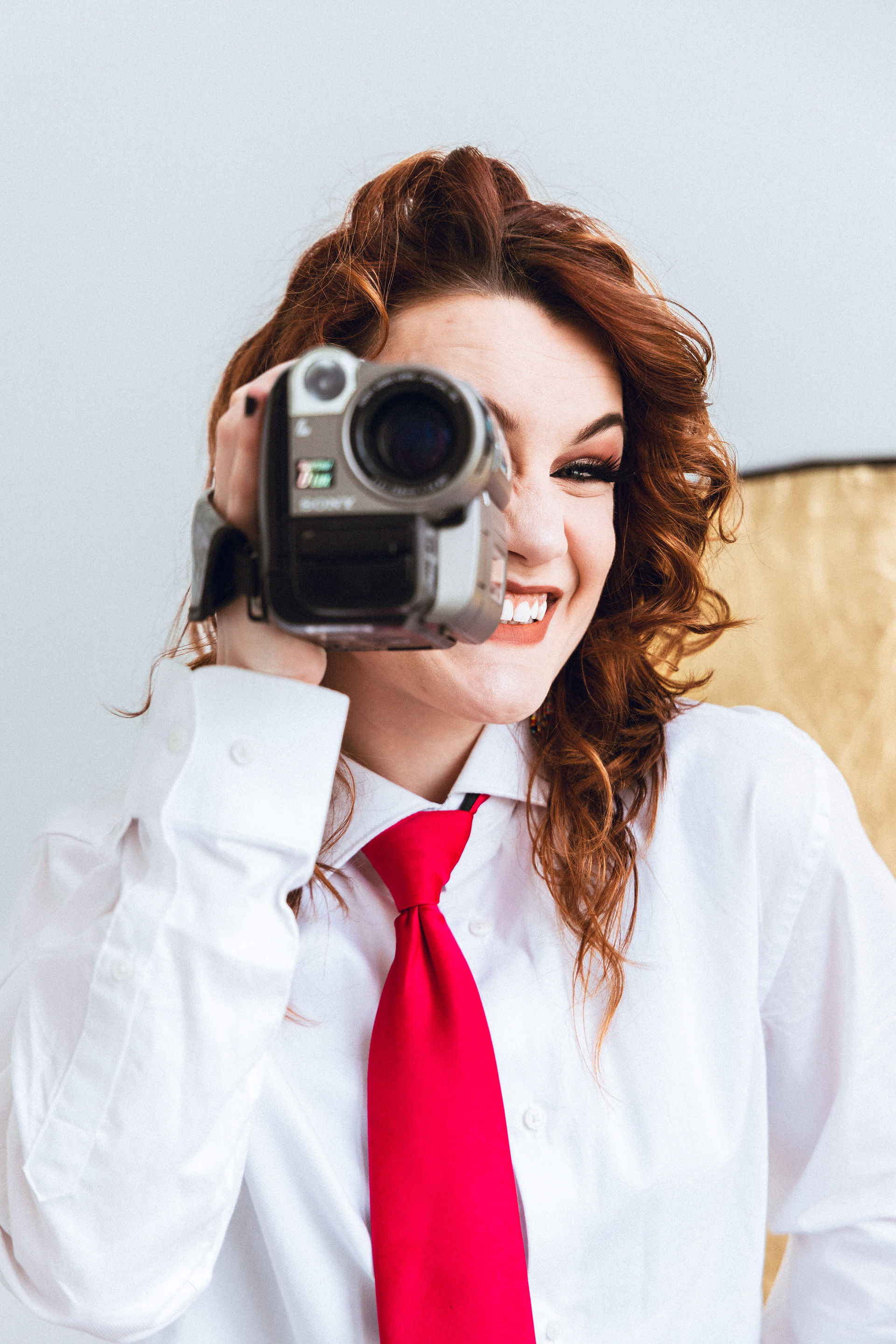 Woman holding a vintage video camera to her eye, smiling