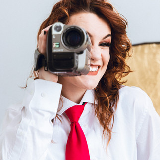 Woman holding a vintage video camera to her eye, smiling