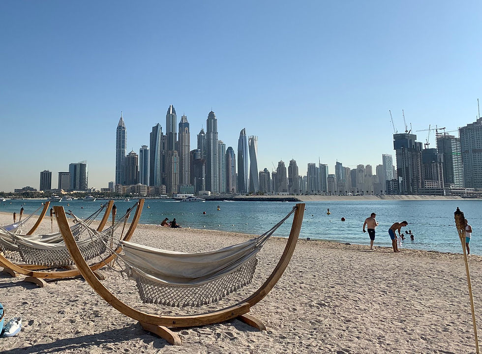 Bright sunny day at palm west beach with modern hammocks and a view of the Dubai skyscrapers skyline