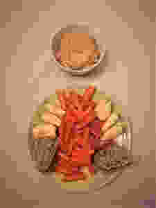 A plate with carrot, apple, bread and a bowl of hummus