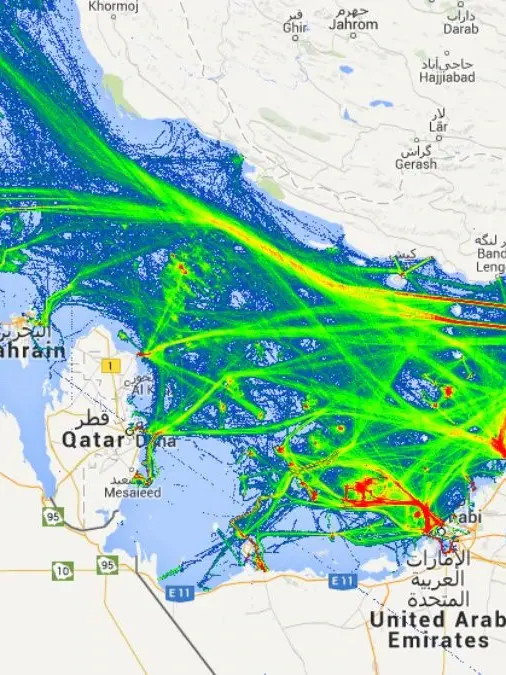 Satellite view of the Strait of Hormuz showing the narrow maritime passage between Iran and Oman with visible commercial shipping lanes and vessel traffic moving between the Persian Gulf and the Gulf of Oman.