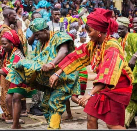 People dancing in colorful traditional Nigerian clothing during a cultural celebration.