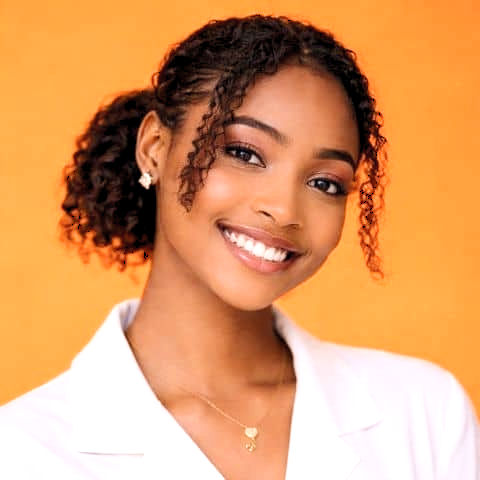 Faith Afolabi smiling in a portrait against a bright orange background.