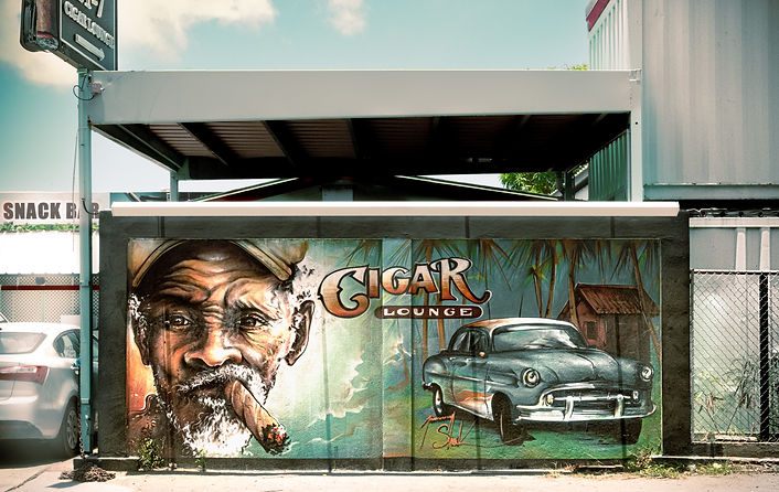 Street art Saint Maarten Caraïbes : fresque murale d’un salon de cigares côté néerlandais avec portrait d'un homme au cigare et voiture ancienne.