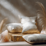 Luxury meditation space with a cream Venetian plaster wall, neutral floor cushions, white and gold feathers, and a glowing pink Himalayan salt lamp in a rose quartz-inspired wellness setting.
