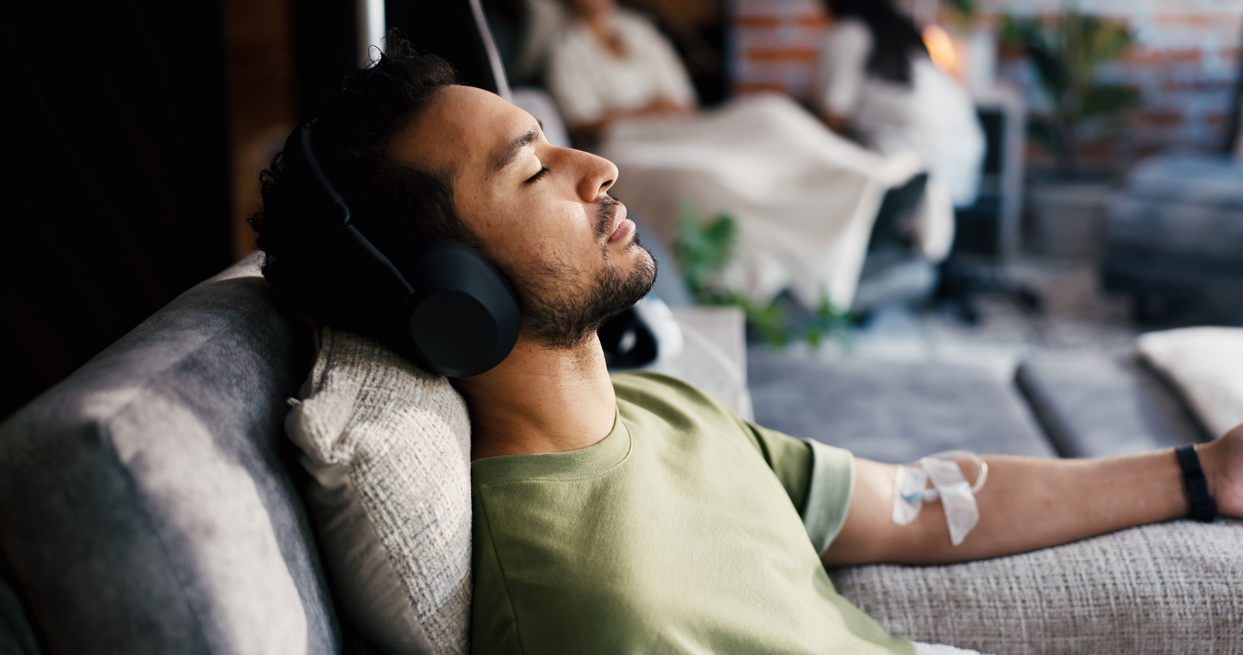 Man relaxing with headphones during IV therapy.