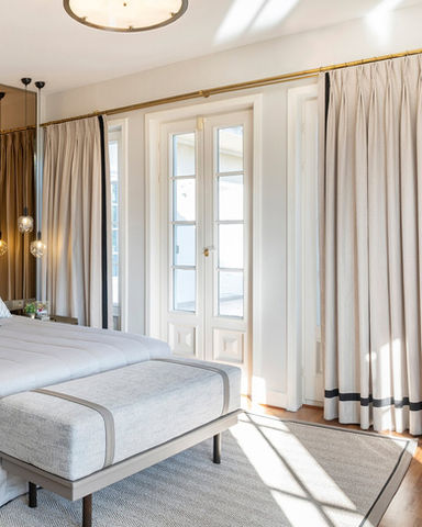 This design features soft neutral drapery enhanced with custom black edge detailing, adding definition and a sophisticated contrast. The double pinch pleat style brings structure and timeless elegance, while the gold curtain rod completes the look with a touch of warmth and luxury.