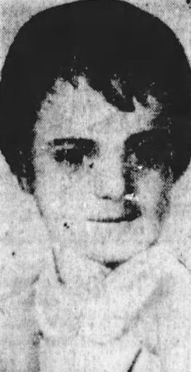 Black and white photo of an older looking toddler with dark short hair and dark eyes. Toddler is very serious looking.