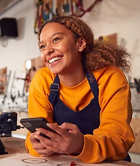 Smiling female bike mechanic using phone and tablet in workshop