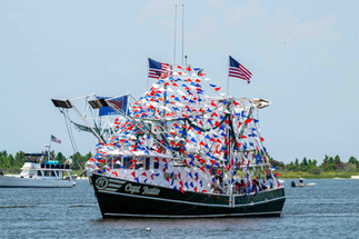 Patriotic-themed boat "Capt. Justin" adorned with red, white, and blue flags at the Biloxi Blessing of the Fleet