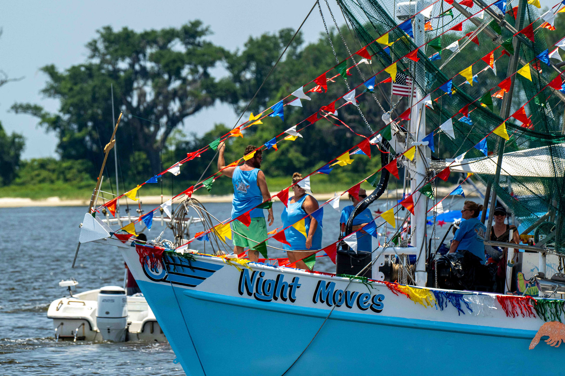 Crew members aboard "Night Moves" shrimp boat celebrate the Blessing of the Fleet in Biloxi with vibrant pennants
