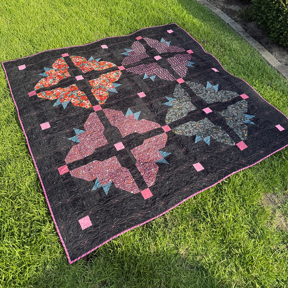Thumbnail: Finished Bats N Bloom Throw quilt displayed outdoors, featuring four large bat and flower-inspired patchwork blocks