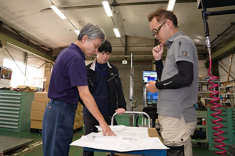 図面を見ながら話し合う従業員3名