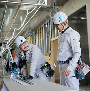 作業する若手の職人と内装会社の社長が会話する様子