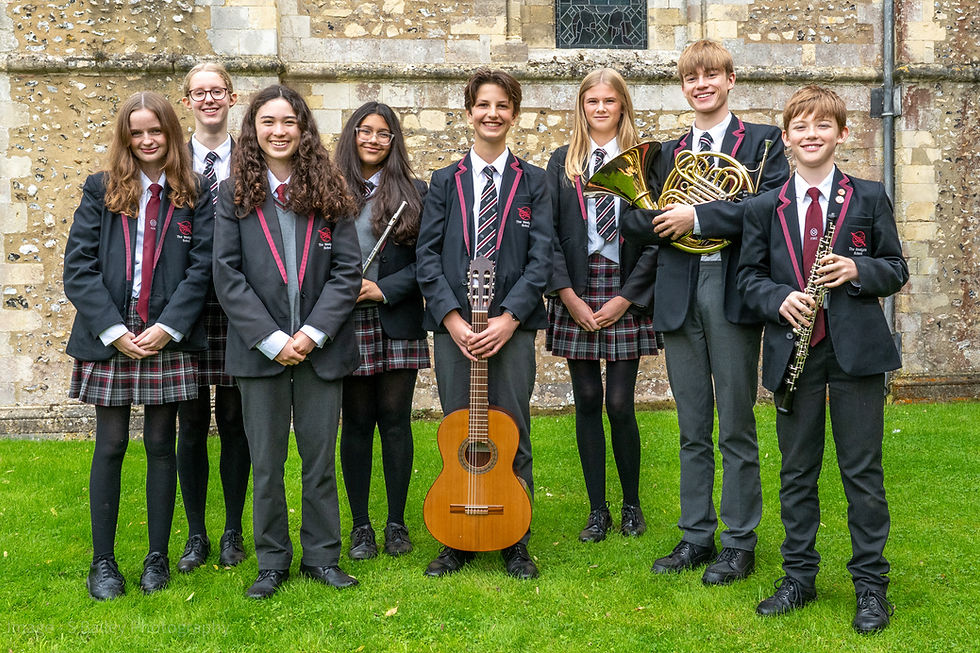 Pupils in front of St Cross in Winchester holding musical instruments