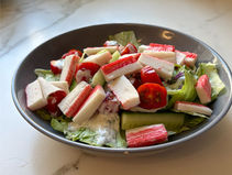 Finalized salad with fresh vegetables and surimi ready to serve